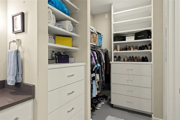 a view of walk in closet with clothes and shoes