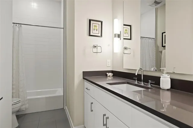 a bathroom with a granite countertop sink a toilet a shower and a mirror