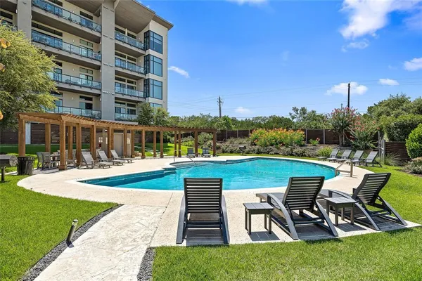 a view of a swimming pool with lawn chairs and a fire pit