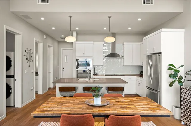 a kitchen with stainless steel appliances granite countertop a refrigerator a sink dishwasher and white cabinets with wooden floor