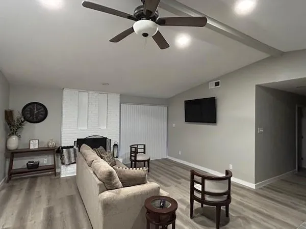 a living room with furniture a flat screen tv and a ceiling fan