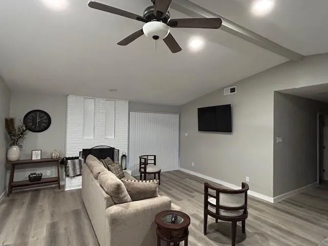 a living room with furniture a flat screen tv and a ceiling fan