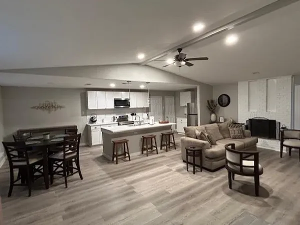 a living room with furniture kitchen view and a wooden floor