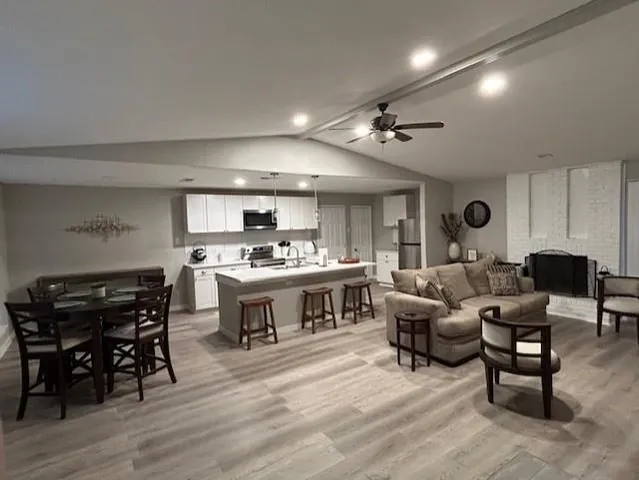 a living room with furniture kitchen view and a wooden floor