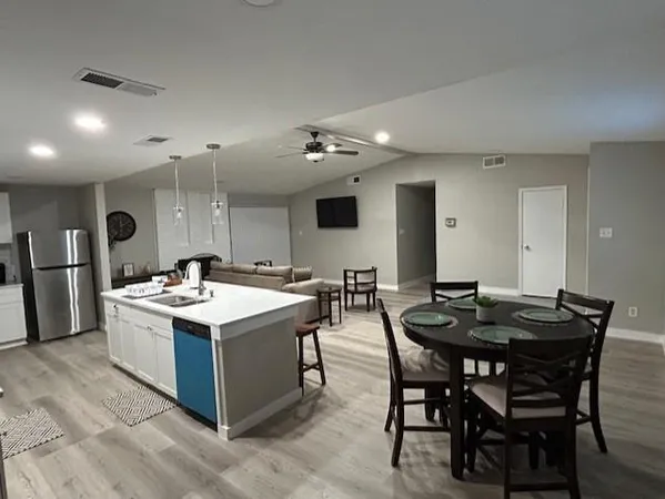 a large kitchen with kitchen island a sink dishwasher a stove and a refrigerator with wooden floor