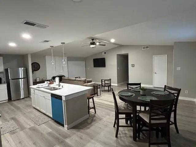 a large kitchen with kitchen island a sink dishwasher a stove and a refrigerator with wooden floor