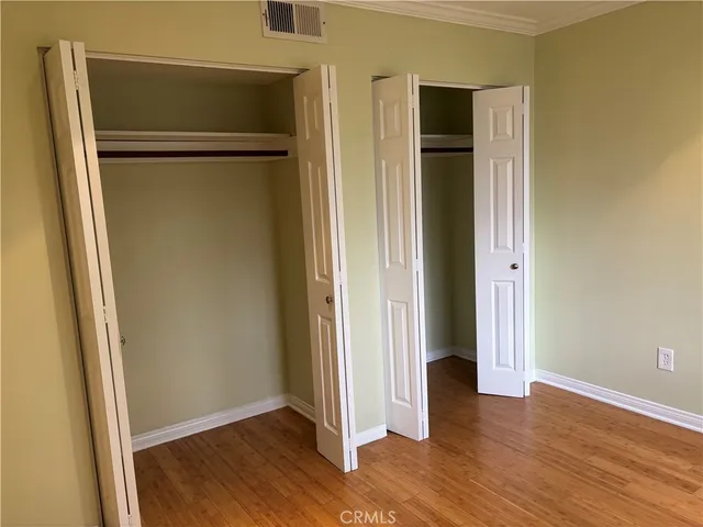 an empty room with wooden floor closet and windows