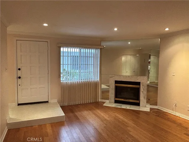 an empty room with wooden floor fireplace and windows