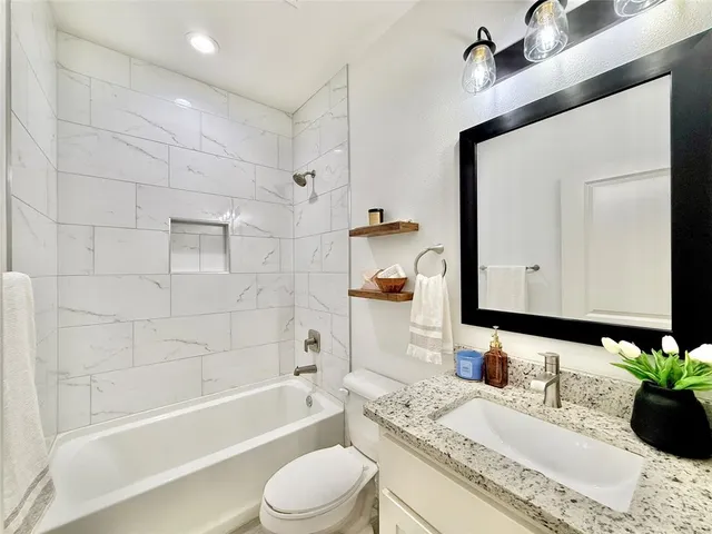 a bathroom with a granite countertop sink vanity mirror bathtub shower and a bathtub