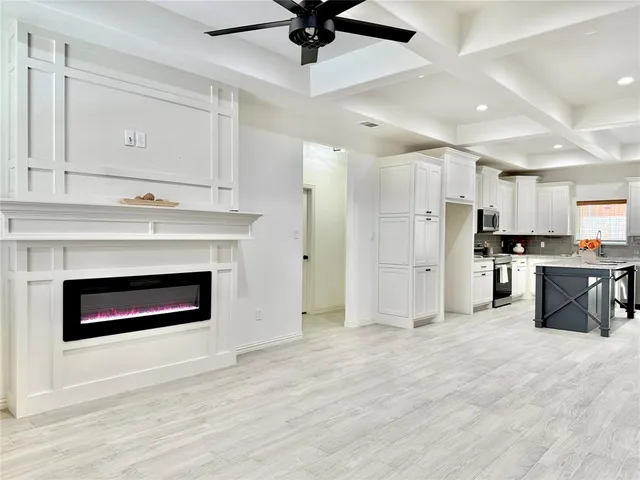 a view of kitchen and empty room with wooden floor