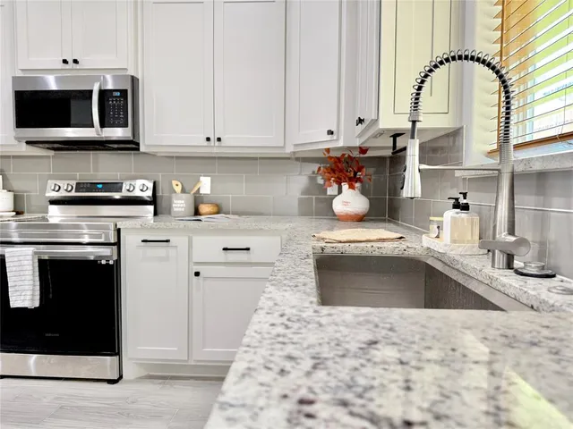a kitchen with stainless steel appliances granite countertop a stove a sink and a microwave