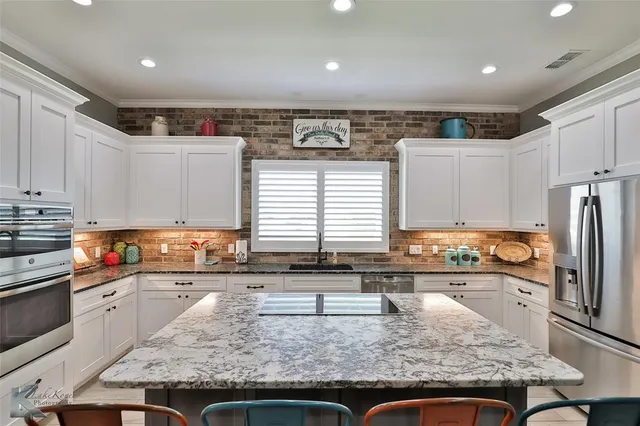 a kitchen with stainless steel appliances granite countertop a sink a stove and a refrigerator