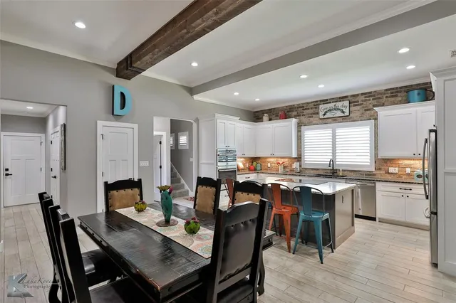 a room with stainless steel appliances kitchen island granite countertop a dining table chairs and granite counter tops