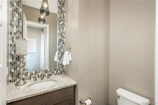 a bathroom with a granite countertop sink and a mirror with toilet