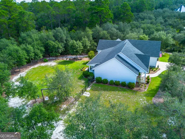 an aerial view of residential house with outdoor space and trees all around