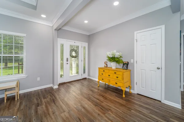 a dining room with wooden floor a chandelier a wooden table and chairs