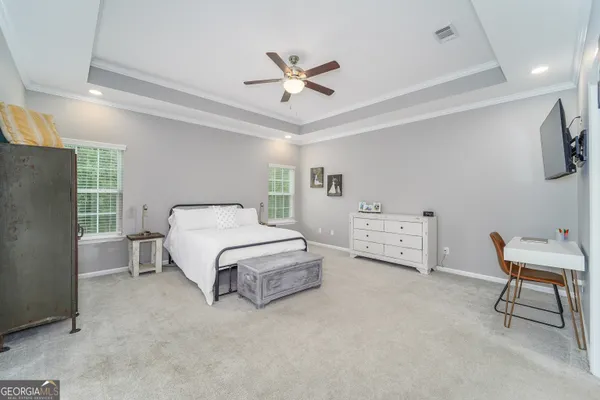 a bedroom with a bed a couch and a flat screen tv