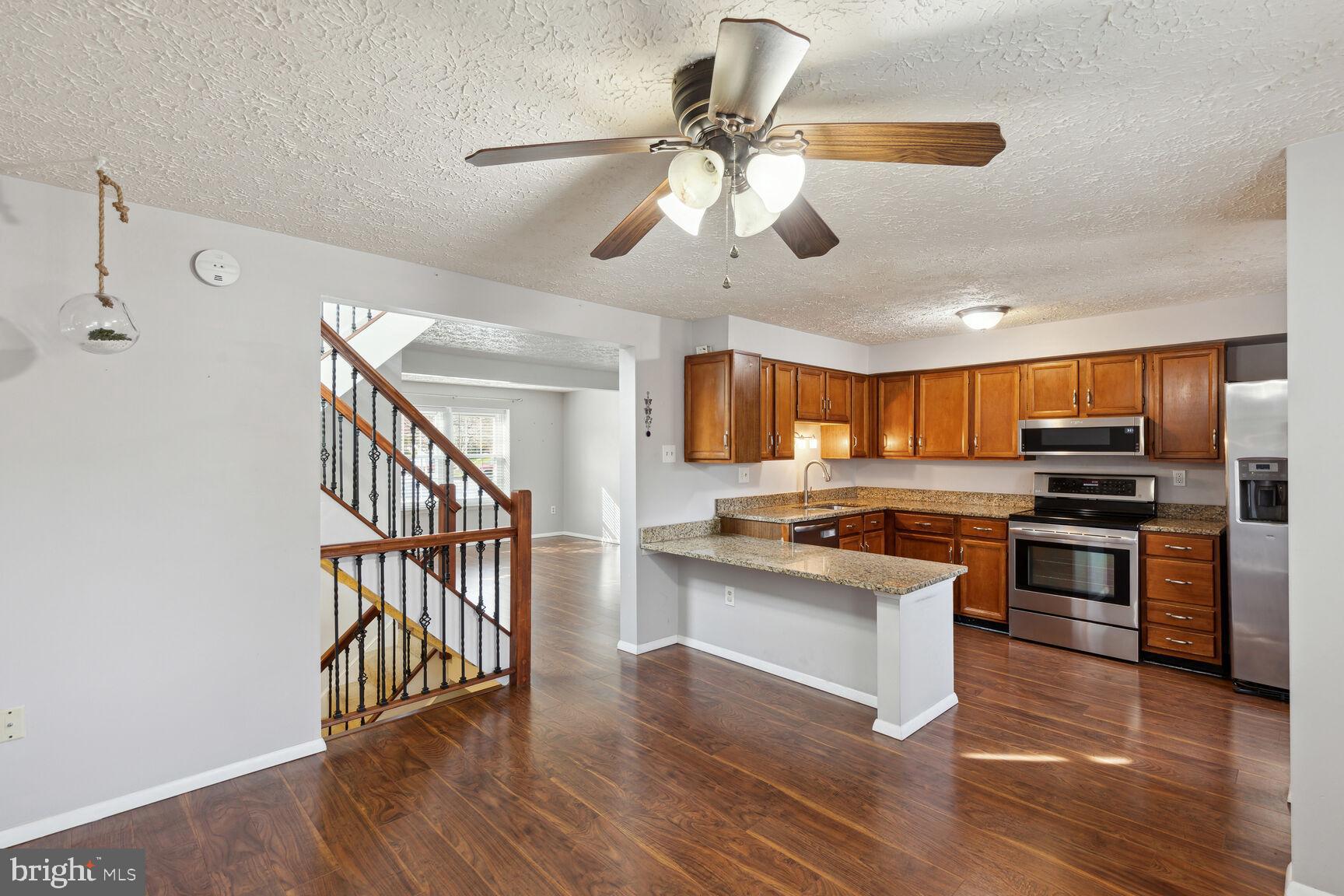 25636 Coltrane Drive Damascus, MD 20872 - Photo 17 of 26 a kitchen with stainless steel appliances kitchen island granite countertop a stove top oven a sink a dining table and chairs with wooden floor