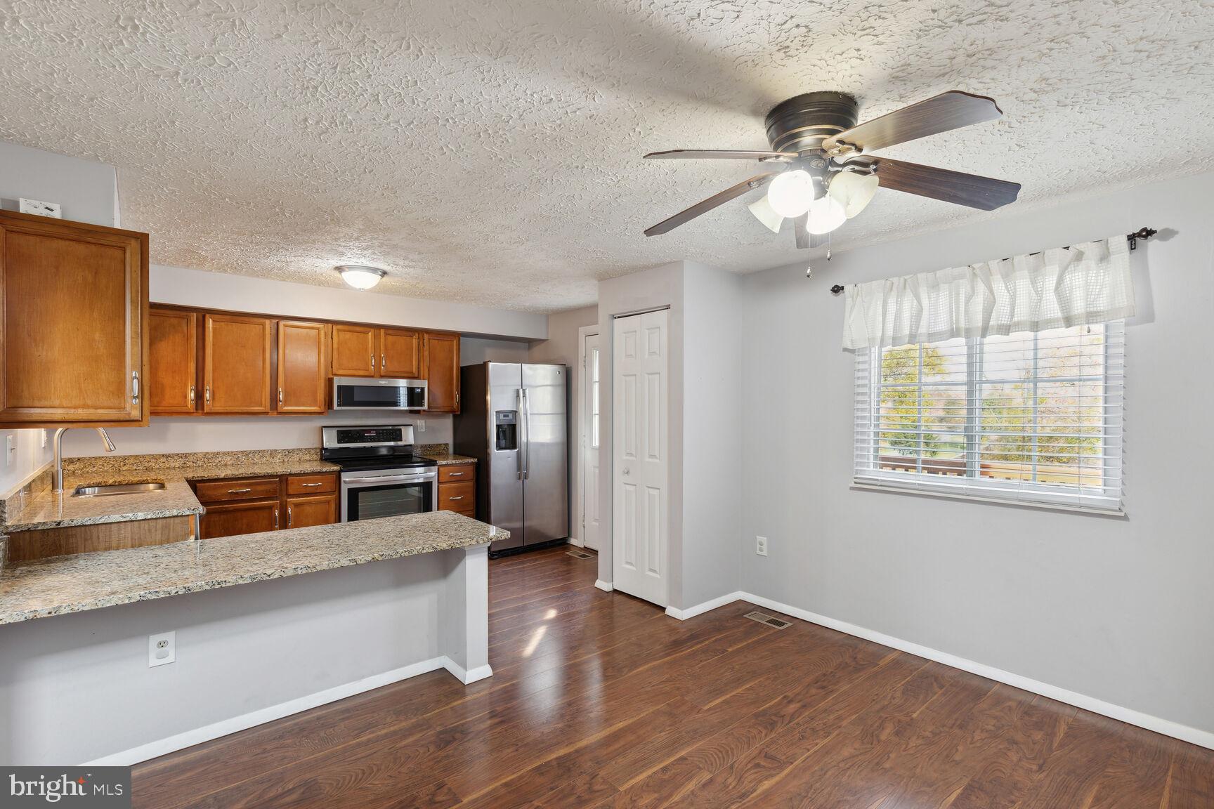25636 Coltrane Drive Damascus, MD 20872 - Photo 2 of 26 a kitchen with stainless steel appliances granite countertop a refrigerator a sink a stove and oven with wooden floor