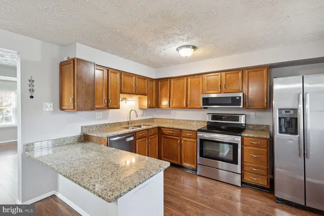 a kitchen with stainless steel appliances granite countertop a sink stove microwave and refrigerator