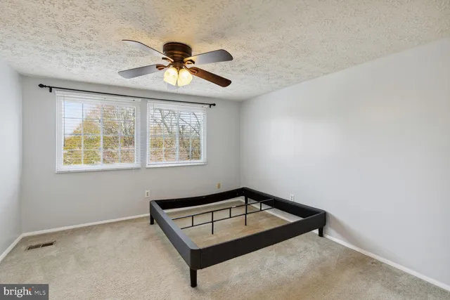 an empty room with windows and ceiling fan