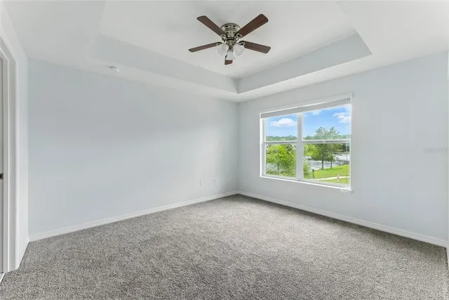 an empty room with windows and ceiling fan