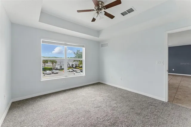 an empty room with windows and fan