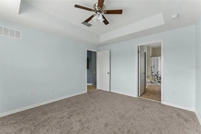 a view of an empty room and chandelier fan