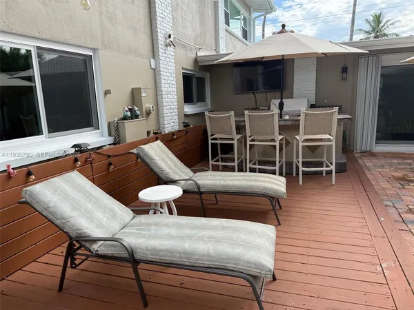 a view of a patio with table and chairs under an umbrella with wooden floor