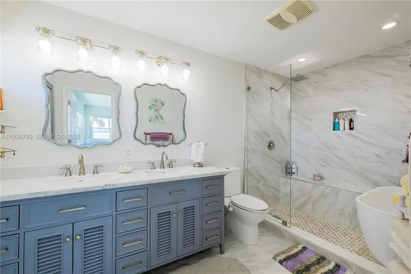a spacious bathroom with a double vanity sink toilet mirror and shower