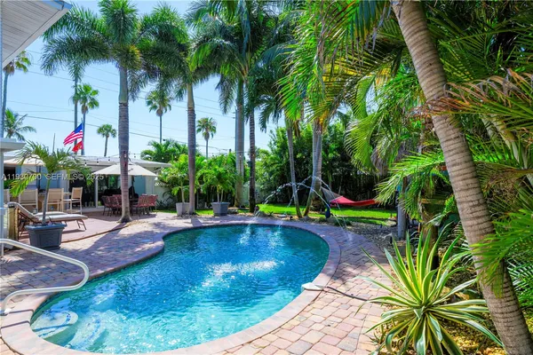 a view of swimming pool with lawn chairs and plants