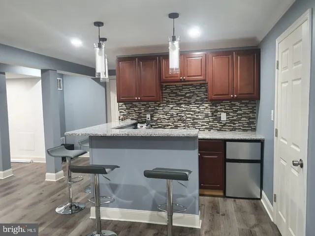 a kitchen with stainless steel appliances kitchen island granite countertop a table chairs in it and wooden floors