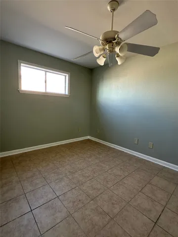 en empty room with windows and ceiling fan