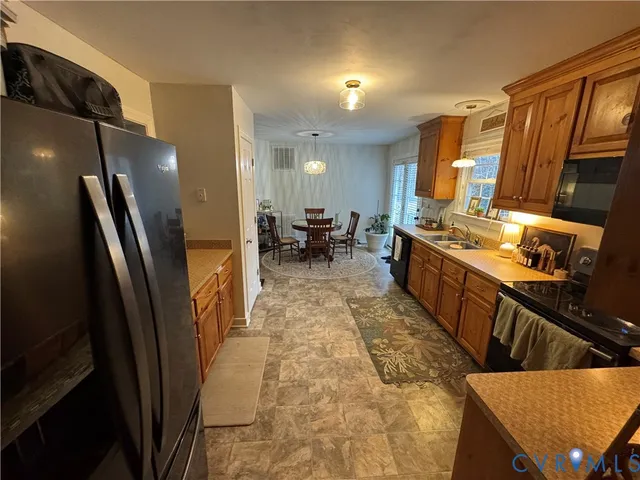 a kitchen with stainless steel appliances granite countertop a refrigerator a stove a sink dishwasher and a dining table with wooden floor