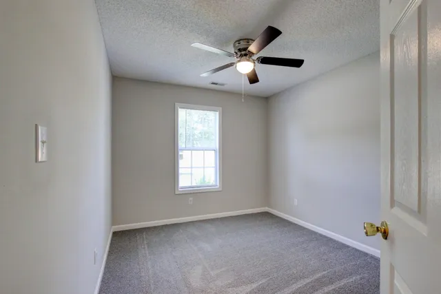 an empty room with windows and fan