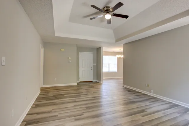 a view of an empty room with a window and wooden floor