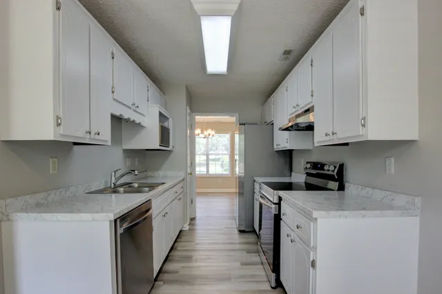 a kitchen with stainless steel appliances granite countertop a stove a sink a refrigerator and white cabinets