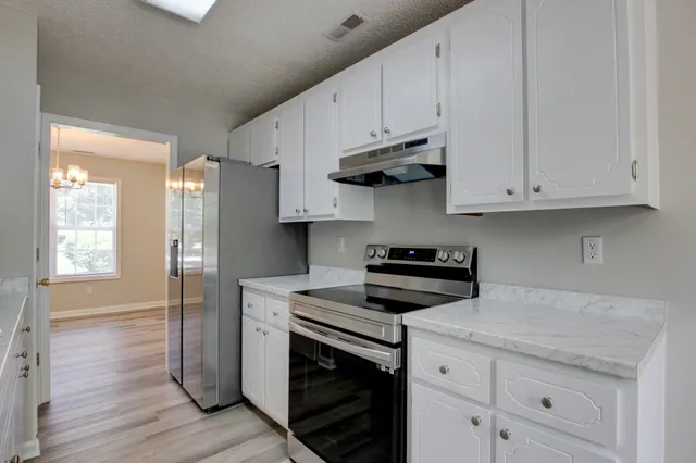 a kitchen with stainless steel appliances granite countertop a stove a sink and white cabinets