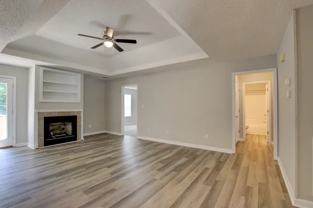 an empty room with wooden floor fireplace and windows