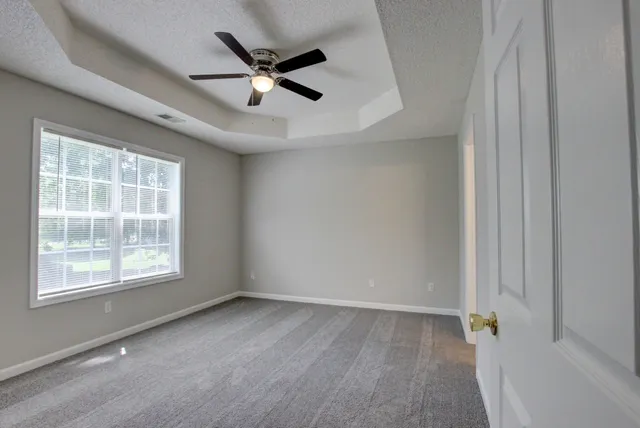 an empty room with windows and fan