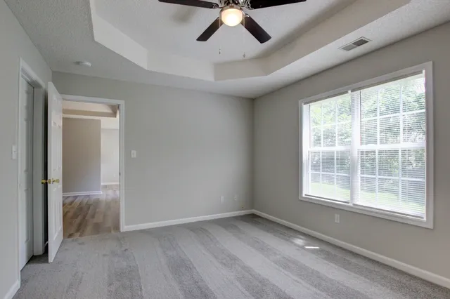 a view of empty room with wooden floor and fan