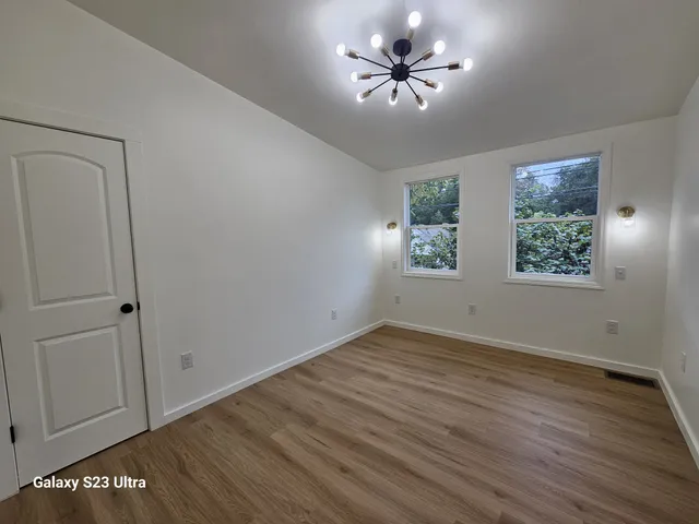 a view of an empty room with a window and wooden floor