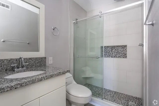 a bathroom with a granite countertop sink toilet and shower