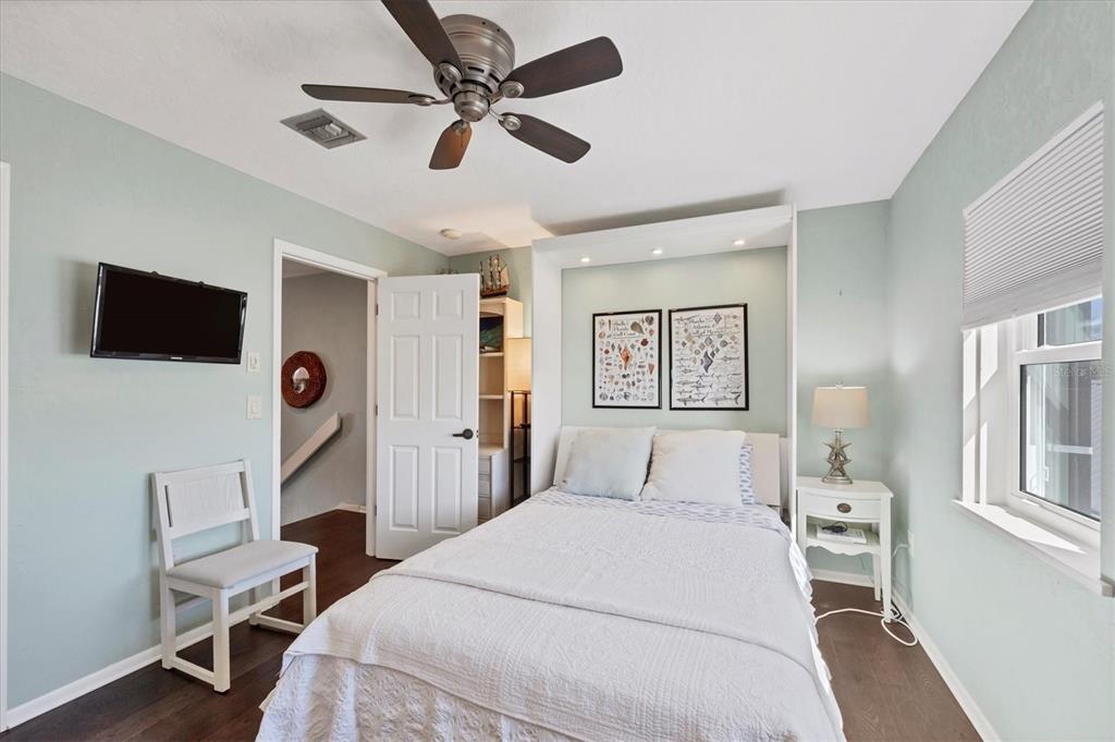 530 5th Street West, Unit 4 Boca Grande, FL 33921 - Photo 32 of 48 a bedroom with a bed a chandelier and a flat screen tv