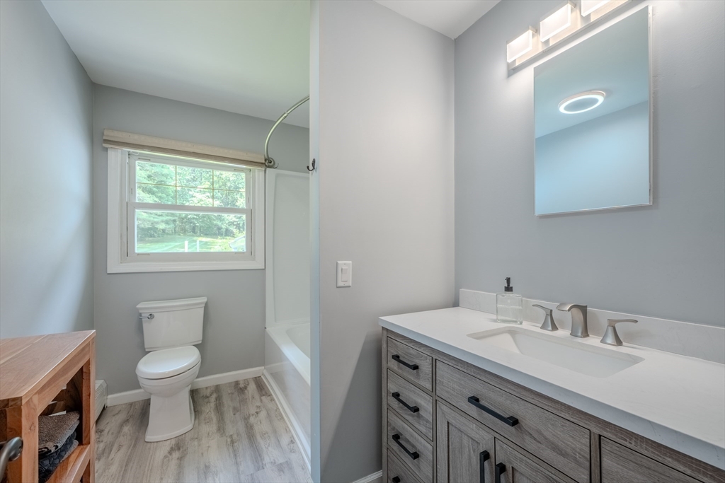 71 Webber Road Brookfield, MA 01506 - Photo 19 of 41 a bathroom with a granite countertop toilet a sink a mirror and a window