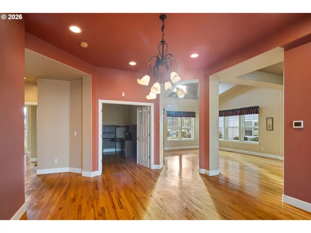 a view of an empty room with wooden floor and a living room