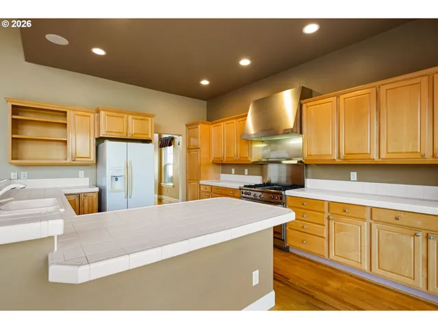 a kitchen with stainless steel appliances kitchen island granite countertop a sink refrigerator and cabinets