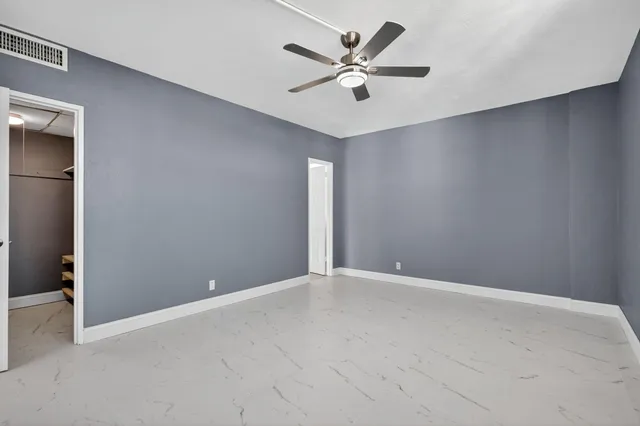 an empty room with windows and fan