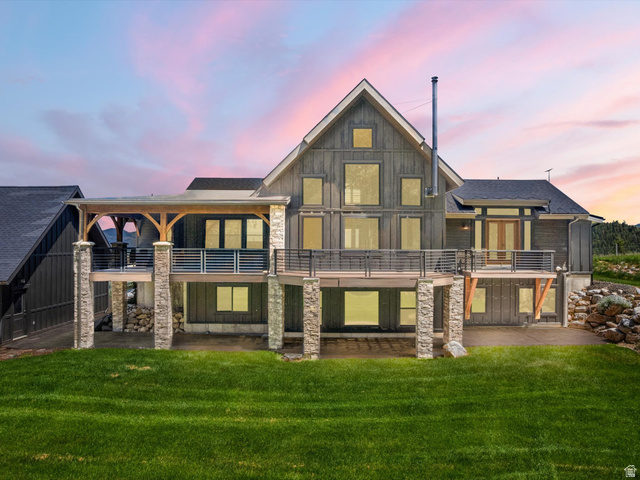 1225 Old Oregon Road Soda Springs, ID 83276 - Photo 67 of 67 Multi-level exterior featuring dark vertical siding, a stone-clad foundation, a covered deck with timber accents, and a lower-level patio