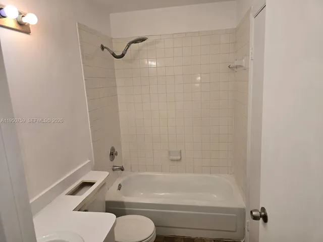 a bathroom with a granite countertop bathtub shower and toilet